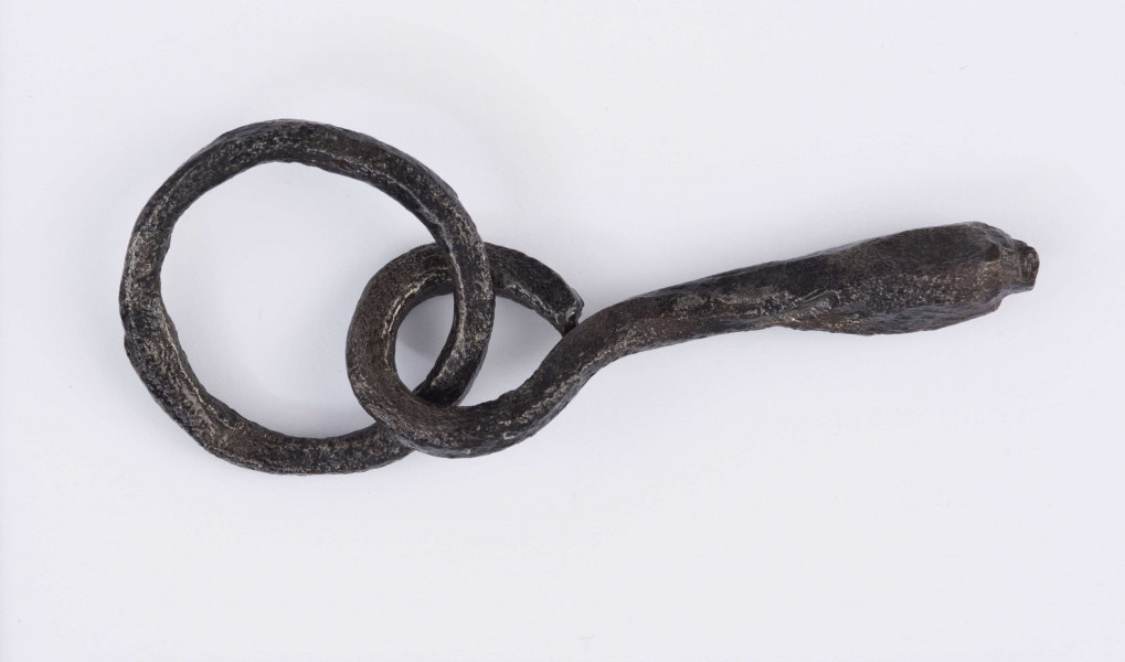 Wędzidło zachowane częściowo, składające się z kołka i zamocowanego do niego fragmentu wędzidła. Kółko w przekroju okrągłe, wędzidło w miejscu połączenia z kółkiem również okrągłe, w części środkowej w kształcie kwadratu o zaokrąglonych rogach.
Wymiary dodatkowe: 0,4 cm (śr. przekroju części w miejscu połączenia); 0,9x0,9 cm (przekrój w częsci środkowej)