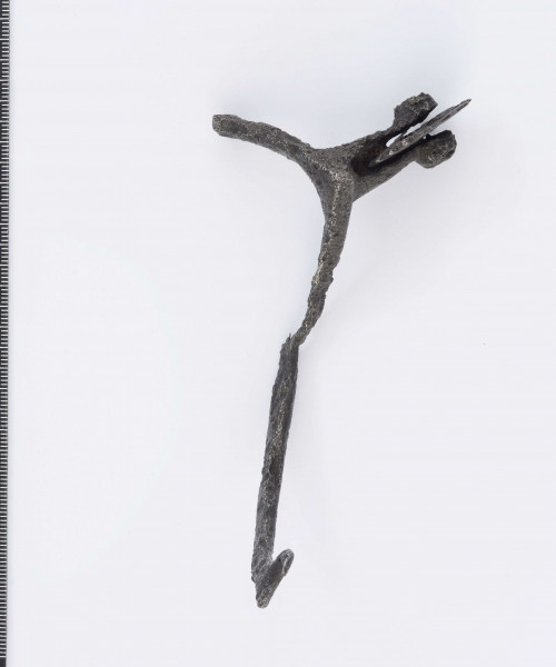 Ostroga żelazna - kabłąk w przekroju poprzecznym trójkątny zakończony kółkiem. Szyjka bodźca zwężająca się, na końcu w rozwidleniu przymocowana nitem gwiazdka (widełki z gwiazdką). Jedno ramie kabłąka uszkodzone, drugie w pobliżu nasady bodźca ułamane. Wymiary: długość ok. 11; rozpiętość kabłąka 10; szyjka dł. 3; średn. gwiazdki 2,5(zachowana); średnica kółka na końcu kabłąka 1,5 cm. Surowiec - żelazo. Stan zachowania - jedno ramię kabłąka uszkodzone, drugie w pobliżu bodźca ułamane. Zabiegi konserwatorskie - zakonserwowane (oczyszczone i zabezpieczone przed korozją).