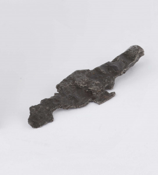 Żelazny grot strzały z wyraźnie wyodrębnionym od tulejki ostrzem; tulejka pełna, płasko sklepana w dolnej partii okrągła; zachowany mały fragment trzpienia