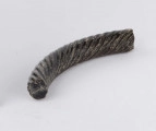 Fragment szklanej bransolety zdobionej kilkoma równolegle do siebie biegnącymi spiralnie wokół bransolety żłobkami. Bransoleta w przekroju okragła. Surowiec - szkło, barwa ciemno-brązowa. Wymiary: dł. 4,2; średn. 0,5 cm. Stan zachowania dobry.