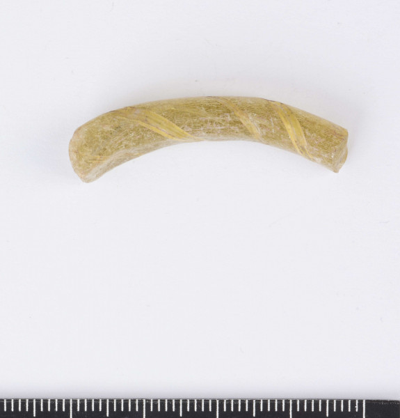 Fragment bransolety szklanej o okrągłym przekroju poprzecznym, miejscami spłaszczona. Wykonana ze szkła o kolorze żółtym z ornamentem spiralnie owijającego paska.