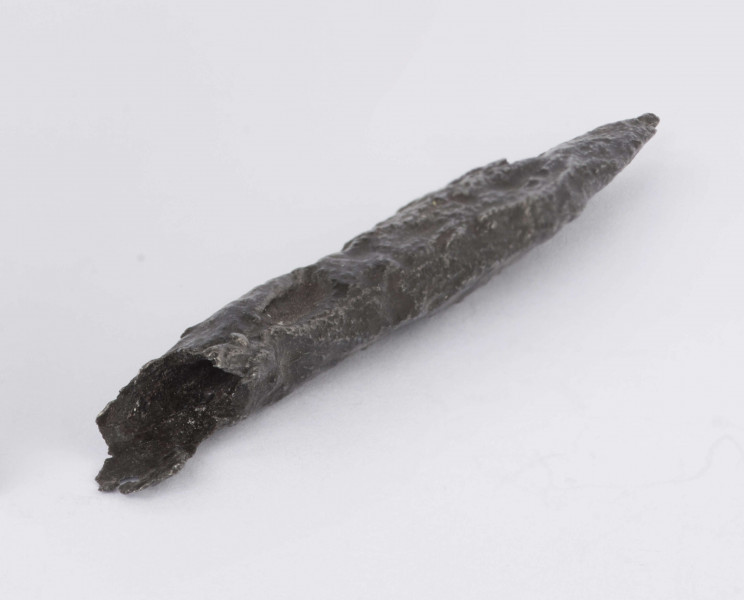 Grot żelazny kształtu lancetowatego. Ostrze z wyraźnym żeberkiem po obu stronach. Tulejka zachowana fragmentarycznie. Surowiec - żelazo. Wymiary: dł. 6,8; szer. ostrza 1; gr. ostrza 0,6 cm. Zabytek zakonserwowano i zabezpieczono przed dalszą korozją. Stan zachowania dobry.