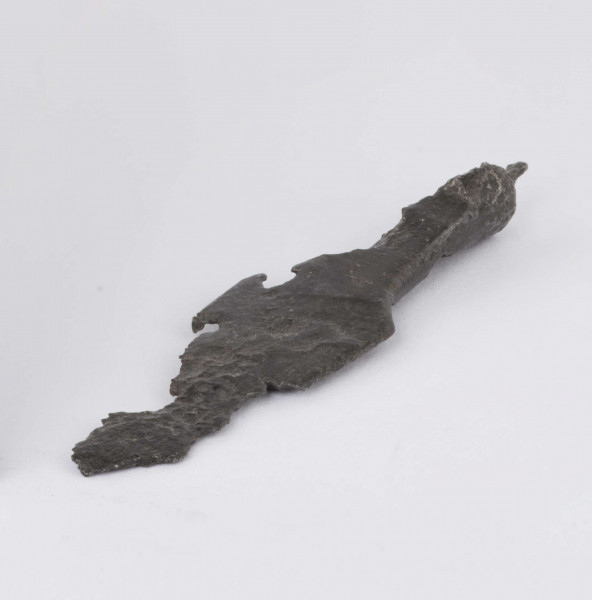 Żelazny grot strzały z wyraźnie wyodrębnionym od tulejki ostrzem; tulejka pełna, płasko sklepana w dolnej partii okrągła; zachowany mały fragment trzpienia