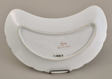 Talerzyk przystawkowy, w kształcie półksiężyca, z wyzębionym brzegiem, biały, z koroną hrabiowską. Spód