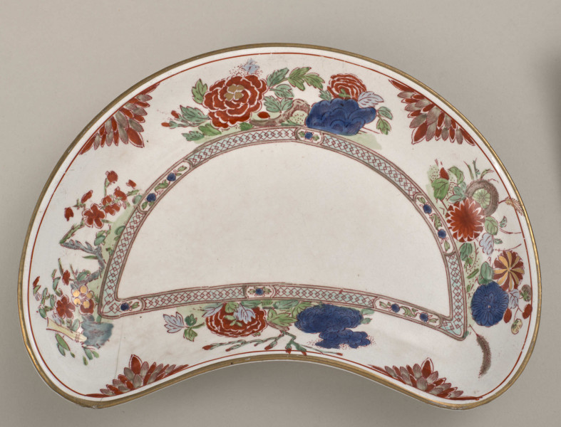 Talerzyk przystawkowy w krztałcie półksiężyca, zdobiony motywem roślinnym, kwiatowym i geometrycznym w kolorze czerwonym