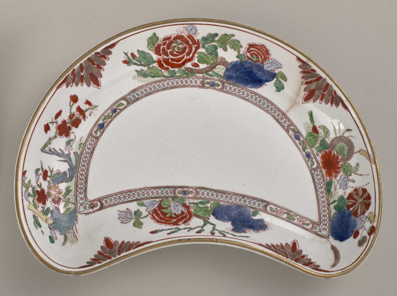 Talerzyk przystawkowy w krztałcie półksiężyca, zdobiony motywem roślinnym, kwiatowym i geometrycznym w kolorze czerwonym