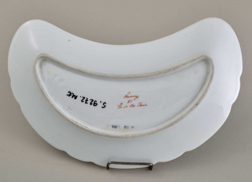 Talerzyk przystawkowy, w kształcie półksiężyca, z wyzębionym brzegiem, biały, z koroną hrabiowską. spód