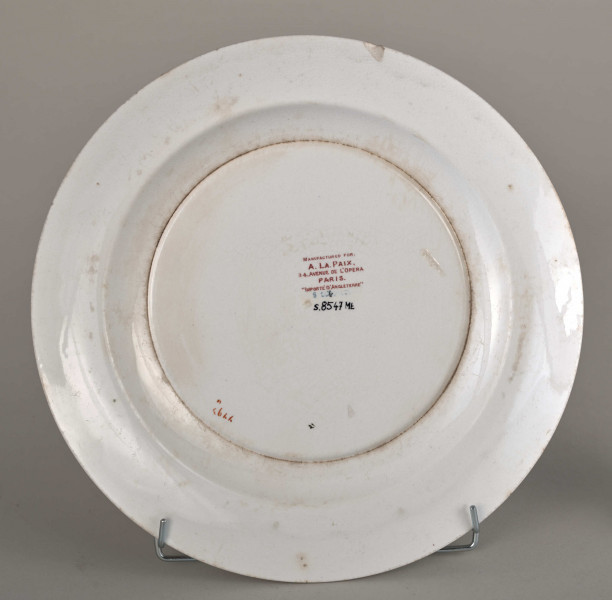 Talerz płytki, zdobiony motywem roślinnym, kwiatowym i geometrycznym w kolorze zielonym, czerwonym, niebieskim i złotym. Spód