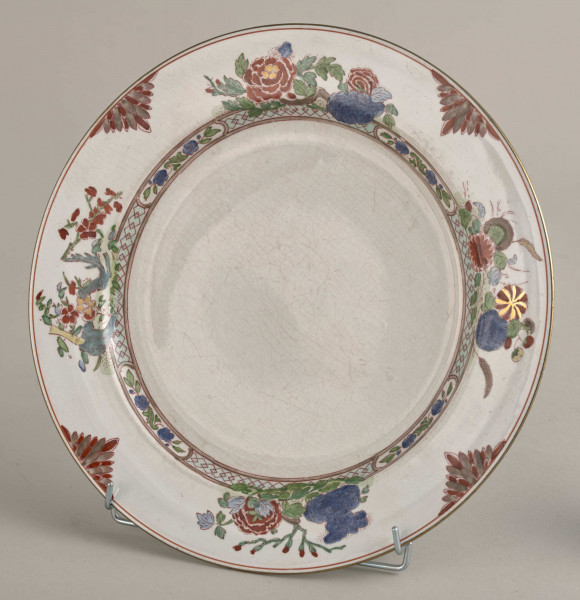 Talerz płytki, zdobiony motywem roślinnym, kwiatowym i geometrycznym w kolorze zielonym, czerwonym, niebieskim i złotym