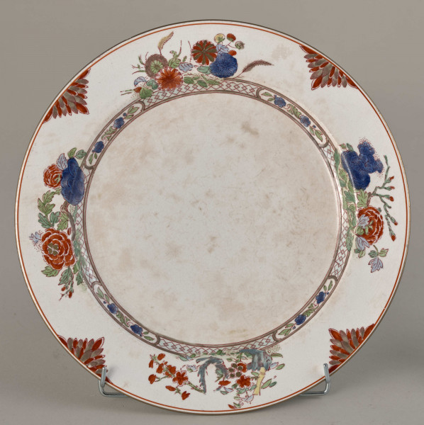 Talerz płytki, zdobiony motywem roślinnym, kwiatowym i geometrycznym w kolorze zielonym, czerwonym, niebieskim i złotym