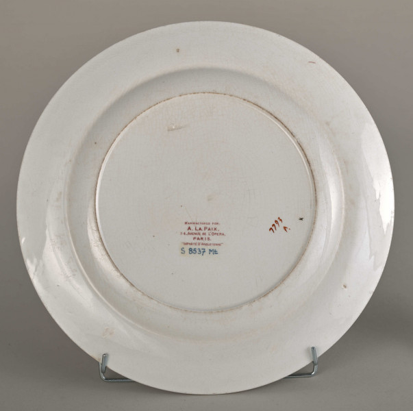 Talerz płytki, zdobiony motywem roślinnym, kwiatowym i geometrycznym w kolorze zielonym, czerwonym, niebieskim i złotym. Spód