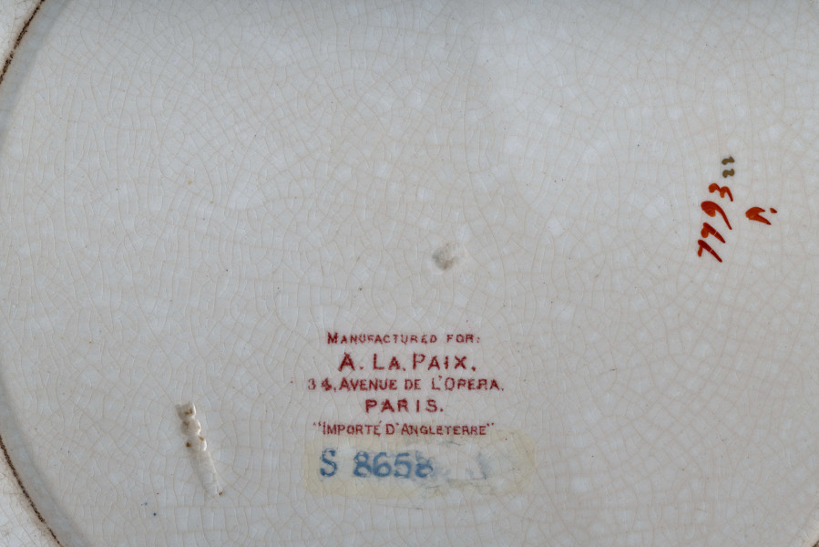 Talerz płytki, zdobiony motywem roślinnym, kwiatowym i geometrycznym w kolorze zielonym, czerwonym, niebieskim i złotym. Nazwa producenta