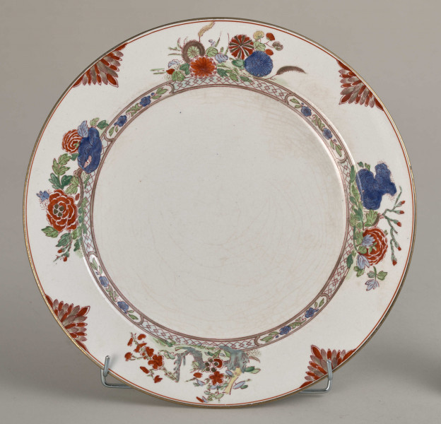 Talerz płytki, zdobiony motywem roślinnym, kwiatowym i geometrycznym w kolorze zielonym, czerwonym, niebieskim i złotym