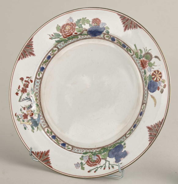 Talerz płytki, zdobiony motywem roślinnym, kwiatowym i geometrycznym w kolorze zielonym, czerwonym, niebieskim i złotym