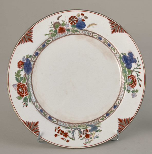 Talerz płytki, zdobiony motywem roślinnym, kwiatowym i geometrycznym w kolorze zielonym, czerwonym, niebieskim i złotym