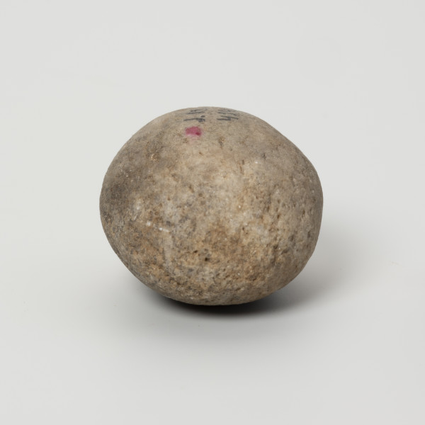 Tłuk - ujęcie z boku; Niewielkich rozmiarów tłuczek kwarcytowy z podstawowego wyposażenia pradziejowych krzemieniarzy. Ten egzemplarz używany był głównie do retuszu oraz przygotowania krawędzi, o czym świadczą wykruszenia zachowane na biegunach i jednym z boków zabytku. Ich orientacja wskazuje, że krzemieniarz, do którego należał tłuk był praworęczny.