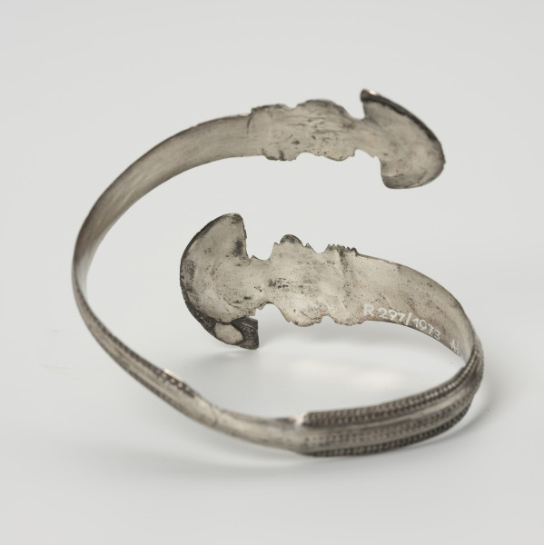 Bransoleta żmijowata - ujęcie z tyłu; Srebrna bransoleta żmijowata. Średnica zakończeń wynosi 2,8 – 2,9 cm. Obie główki (zakończenia) bransolety posiadają szerokie ornamentowane kryzy.