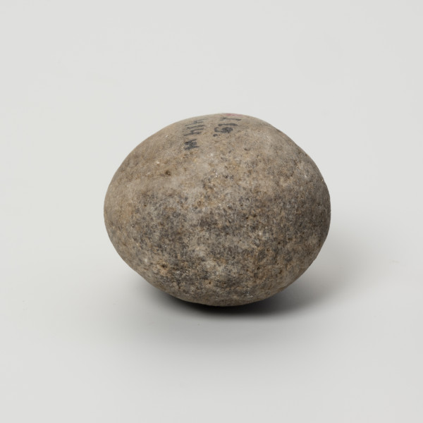 Tłuk - ujęcie z drugiego boku; Niewielkich rozmiarów tłuczek kwarcytowy z podstawowego wyposażenia pradziejowych krzemieniarzy. Ten egzemplarz używany był głównie do retuszu oraz przygotowania krawędzi, o czym świadczą wykruszenia zachowane na biegunach i jednym z boków zabytku. Ich orientacja wskazuje, że krzemieniarz, do którego należał tłuk był praworęczny.