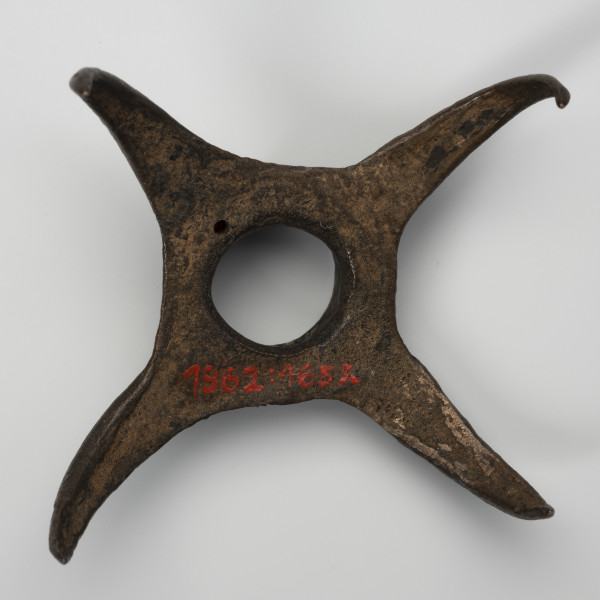 Pobocznica wędzidła końskiego (krępulec) - ujęcie z dołu; Krępulec tzw. kolczasty złożony jest z niewielkiej tulejki zaopatrzonej w cztery kolczaste ramiona lekko zagięte do środka. Przedmiot wykonany jest z brązu.