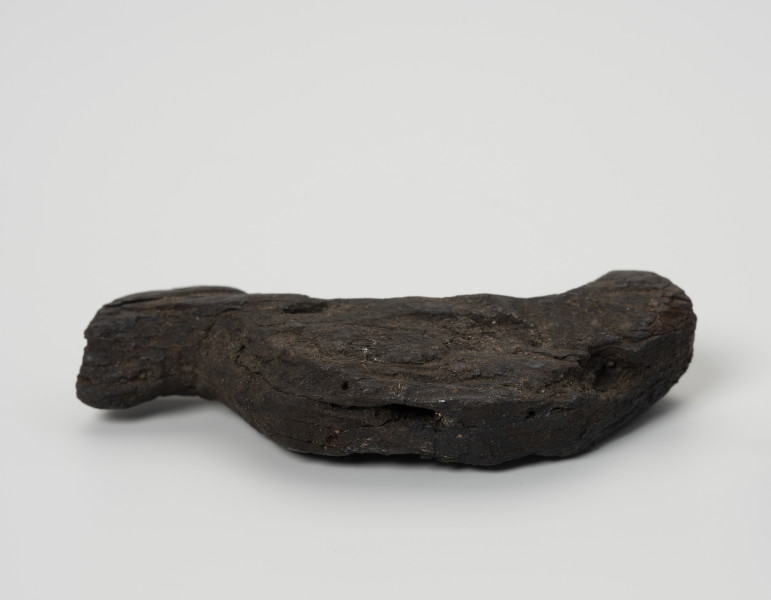 Ptaszek z kory - ujęcie z dołu; Figurka ptaszka wystrugana z kory o schematycznej sylwetce. Wyodrębniona została jedynie głowa i ogon bez pozostałych typowych cech ptasich. Powierzchnia wykończona starannie, bez zadziorów.