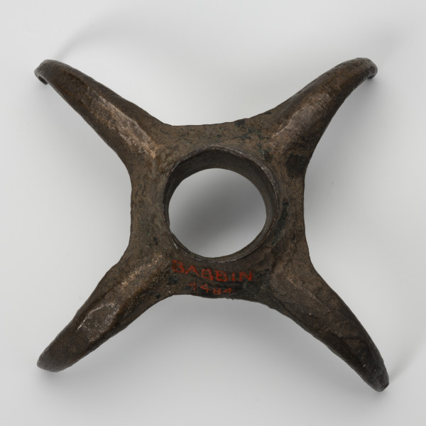 Pobocznica wędzidła końskiego (krępulec) - ujęcie z góry; Krępulec tzw. kolczasty złożony jest z niewielkiej tulejki zaopatrzonej w cztery kolczaste ramiona lekko zagięte do środka. Przedmiot wykonany jest z brązu.