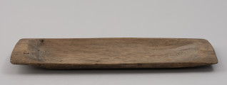tacka do sznurów haczykowych - ujęcie z boku; Płytka, drewniana niecka, wykonana techniką stolarską z jednego kawałka drewna. Naroża lekko zaokrąglone. Na jednym z końców niecki, przy krawędziach dłuższych boków, po jednym otworze, przez który przechodzi drut, służący do mocowania haczyków.