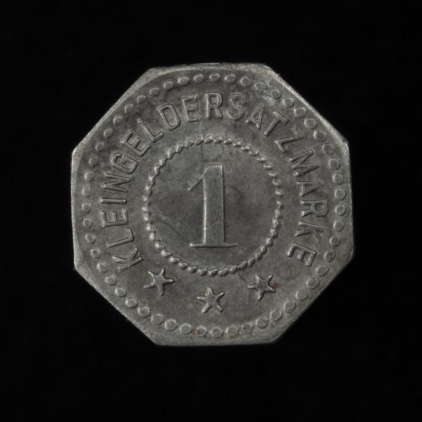 1 fenig - rewers; Ośmioboczna moneta domu handlowego Rudolf Karstadt w Szczecinie z gładkim rantem. Rewers: w polu w sznurowej obwódce cyfra 1, powyżej po łuku napis KLEINGELDERSATZMARKE, a poniżej ustawione po łuku trzy pięcioramienne gwiazdki; obwódka zewnętrzna perełkowa.