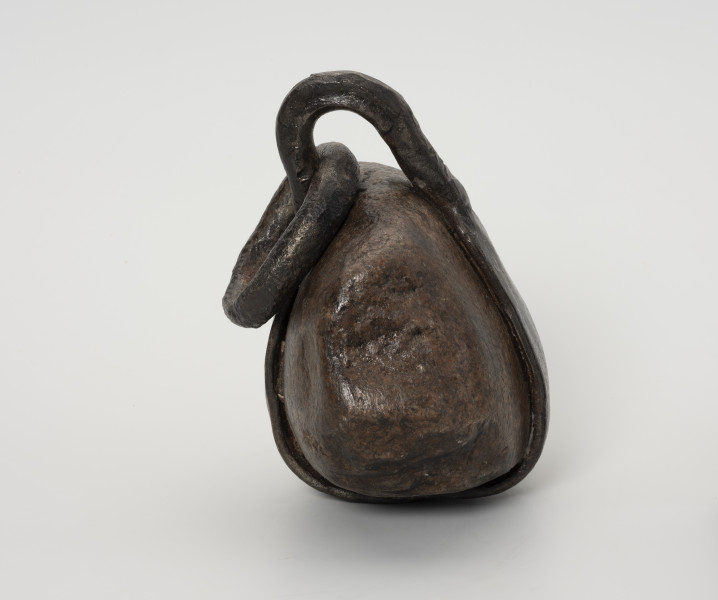 Ciężarek do sieci - ujęcie z drugiego boku; Ciężarek do obciążania sieci wykonany z kamienia. W środkowej części kamień otoczony wykutym z żelaza, spłaszczonym pierścieniem. W części górnej pierścień wystaje poza obręb kamienia tworząc pętlę, przez którą przechodzi owalne, żelazne ogniwo, służące przymocowaniu ciężarka do sieci.