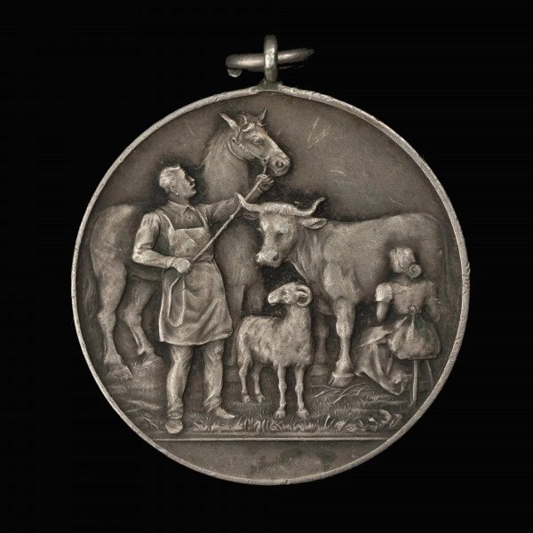 Medal nagrodowy Izby Rolniczej Prowincji Pomorze - rewers; Okrągły medal z kompozycją herbową i realistyczną, z uszkiem i koluszkiem. Na rewersie mężczyzna w fartuchu trzymający za uzdę konia, obok kobieta dojąca krowę, pośrodku stojący baran.