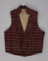 Kamizelka męska - ujęcie z przodu; Kamizelka część męskiego stroju z półwyspu Mönchgut na Rugii/Niemcy. Przód z tkaniny wełnianej, prawdopodobnie wykonanej na krosnach tkackich, wzór w wąskie paski ułożone na kamizelce poprzecznie w kolorach: czerwonym, szarym, brązowym i białym. Pod szyją wysoka stójka, klapy szeroko wyłożone zapinane na górze na mosiężne guziki. Zapięcie dwurzędowe na 7 mosiężnych guzików. Pod stójką, po obu jej stronach  po jednym mosiężnym guziku ( forma ozdoby). Na bokach małe wpuszczane kieszonki, dół zakończony prosto. Podszewka z białego lnianego płótna wykonanego na krosnach tkackich splotem płóciennym prostym.