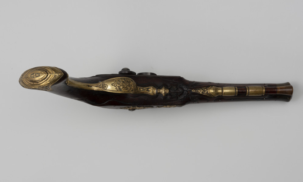 Para pistoletów kapiszonowych - ujęcie z dołu; Pistolet kapiszonowy, pojedynkowy. Lufa stalowa okrągła. W części dennej lufy napis: G.G. EWERTZ STETTIN. Zamek kapiszonowy zdobiony motywami roślinnymi, mocowany za pomocą dwóch śrub. Kabłąk ozdobiony rocaillowym wzorem. Kolba z drewna orzechowego. Łoża i rękojeść rzeźbiona w motywy rocaillowe. Pobojczyk i łoże u wylotu lufy zakończone kościanymi nakładkami. U spodu łoża dwie miedziane tulejki przytrzymujące pobojczyk. Głowica kolby jest spłaszczona, jej okucie jest mosiężne, zdobione motywem roślinnym.