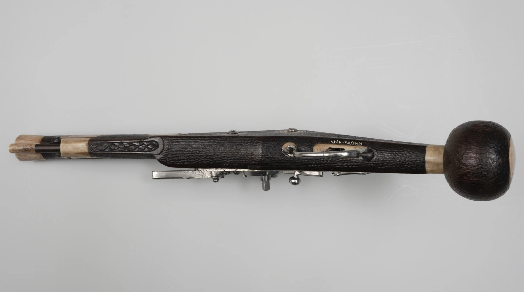 Puffer (pistolet z zamkiem kołowym) - ujęcie z dołu; Lufa stalowa przy wylocie pogrubiona. Warkocz długości 5,2 cm. Zamek wykonany ze stali. Język stalowy prosty. Łoże z jasnego drewna przyciemnionego na kolor brązowy, o fakturze przypominającej wytłaczaną skórę. Kolba lekko pochylona, zakończona kolistą drewnianą głowicą.