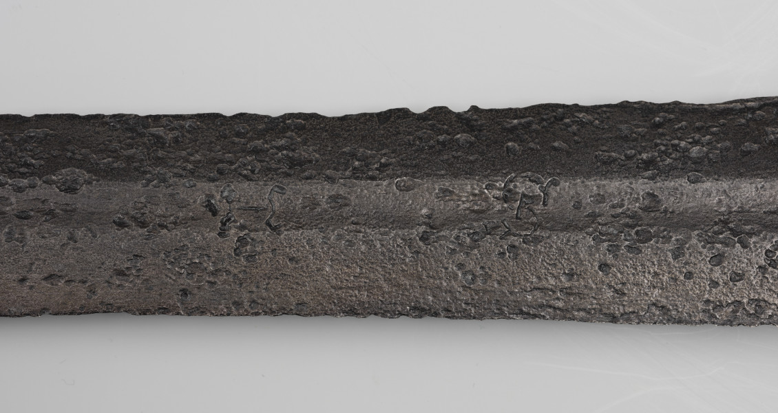 Miecz dwuręczny typu XVII (Oakeshott) - detal; Widoczny fragment żelaznego, srebrnego miecza. Fragment głowni miecza.
