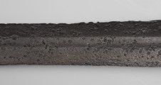 Miecz dwuręczny typu XVII (Oakeshott) - detal; Widoczny fragment żelaznego, srebrnego miecza. Fragment głowni miecza.