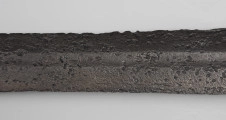 Miecz dwuręczny typu XVII (Oakeshott) - detal; Widoczny fragment żelaznego, srebrnego miecza. Fragment głowni miecza.