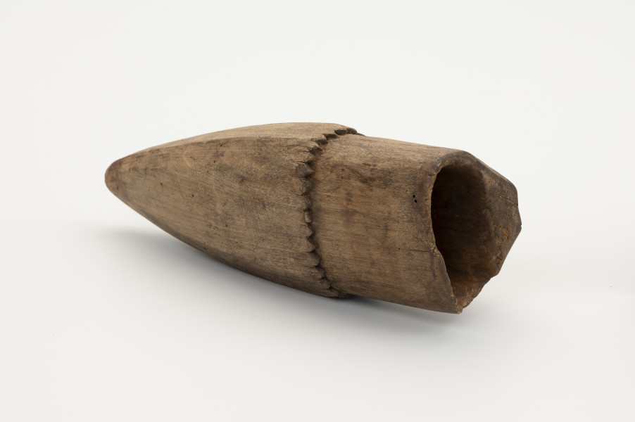 Pochewka na osełkę - ujęcie z góry; Pojemnik drewniany do przechowywania osełki z jednego kawałka ﻿drewna. Górna część o przekroju kwadratowym. Środek wydrążony. Poniżej otworu dookolnie wycięte ozdobne ząbki, poniżej których pochwa przybiera stożkowaty kształt.