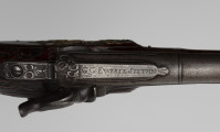 Para pistoletów kapiszonowych - detal; Fragment pistoletu kapiszonowego, pojedynkowego. Zamek kapiszonowy przerobiony ze skałkowych, zdobiony motywami roślinnymi i grawerowanym napisem: G.G. EWERTZ STETTIN.