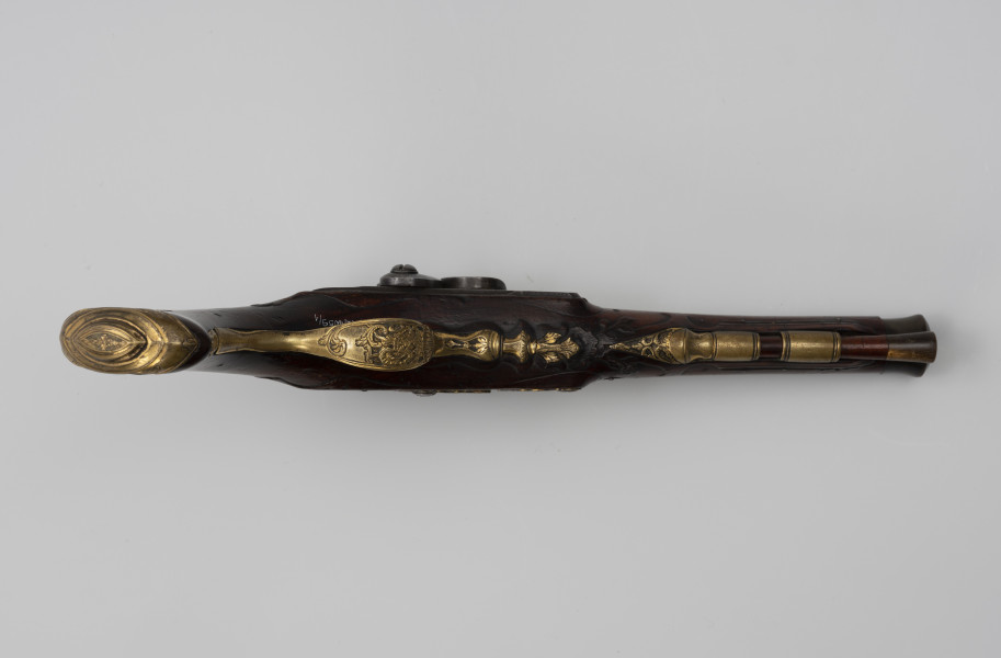 Para pistoletów kapiszonowych - ujęcie z dołu; Pistolet kapiszonowy, pojedynkowy. Lufa stalowa okrągła. W części dennej lufy napis: G.G. EWERTZ STETTIN. Zamek kapiszonowy zdobiony motywami roślinnymi, mocowany za pomocą dwóch śrub. Kabłąk ozdobiony rocaillowym wzorem. Kolba z drewna orzechowego. Łoża i rękojeść rzeźbiona w motywy rocaillowe. Pobojczyk i łoże u wylotu lufy zakończone kościanymi nakładkami. U spodu łoża dwie miedziane tulejki przytrzymujące pobojczyk. Głowica kolby jest spłaszczona, jej okucie jest mosiężne, zdobione motywem roślinnym.