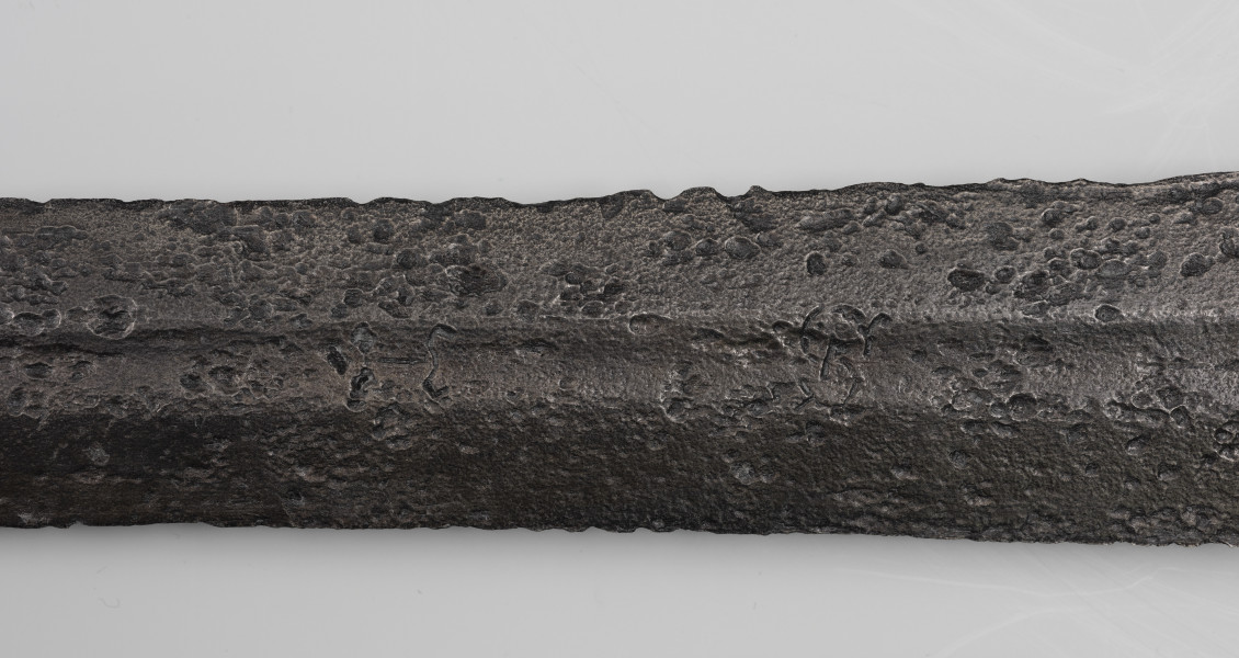 Miecz dwuręczny typu XVII (Oakeshott) - detal; Widoczny fragment żelaznego, srebrnego miecza. Fragment głowni miecza.