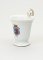 Filiżanka - ujęcie z boku; Filiżanka z grubej, białej porcelany w kształcie odwróconego dzwonu. Czara wysoka, łagodnie rozszerzająca się ku górze, z wylewem wywiniętym na zewnątrz. Stopa niska, okrągła, rozpłaszczona na zewnątrz, z pierścieniem na styku z czarą. Uszko wysokie, wyniesione ponad poziom wylewu w kształcie zwiniętego zwieńczenia pastorału; doklejone do wnętrza jej wylewu. Czara ozdobiona w centrum, po przeciwnej stronie uszka, malowaną naszkliwnie barwną tarczą z herbem Szczecina - profil głowy gryfa w koronie. Tarczę z bocznymi wcięciami wieńczy corona muralis a pod herbem napis Stettin. Ślady złoceń wokół wylewu od środka czary, na brzegu stopy oraz na uchwycie.