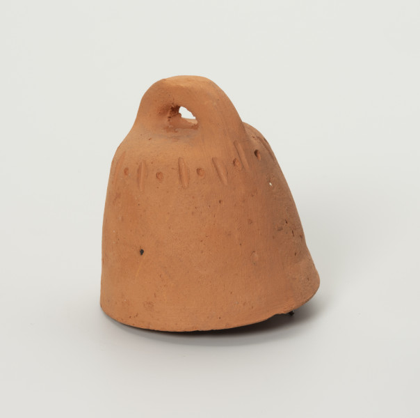 Dzwonek Heleny Kurcyusz - ujęcie z przodu; Gliniany dzwonek kloszowy, bez wyraźnie wyodrębnionego płaszcza i wieńca. Szeroka korona w dwóch przeciwległych miejscach nachodzi na brzegi hełmu i górnej krawędzi. Zdobiony przy krawędzi górnej prostym, dookolnym ornamentem z rytych naprzemiennie pionowych kresek i punktów.