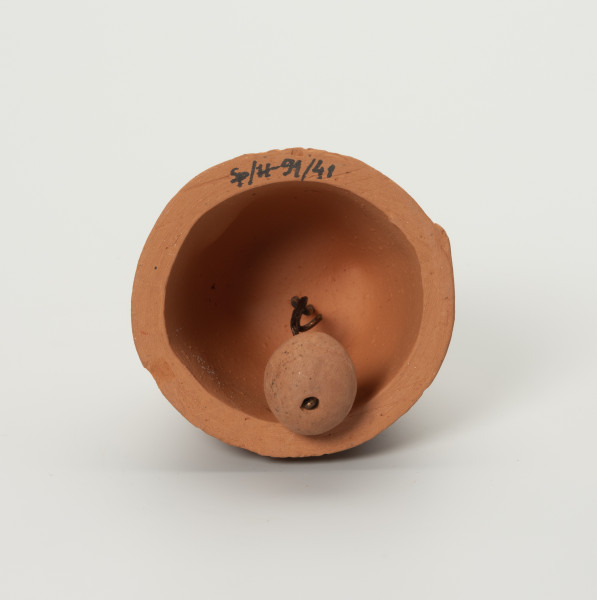 Dzwonek Heleny Kurcyusz - ujęcie z dołu; Gliniany dzwonek kloszowy. Serce dzwonka, w kształcie gruszkowate, zostało zawieszone na wewnętrznej zawieszce przy pomocy sznurka.