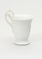 Filiżanka - ujęcie z drugiego boku; Filiżanka z grubej, białej porcelany w kształcie odwróconego dzwonu. Czara wysoka, łagodnie rozszerzająca się ku górze, z wylewem wywiniętym na zewnątrz. Stopa niska, okrągła, rozpłaszczona na zewnątrz, z pierścieniem na styku z czarą. Uszko wysokie, wyniesione ponad poziom wylewu w kształcie zwiniętego zwieńczenia pastorału; doklejone do ścianki czary i wnętrza jej wylewu. Ślady złoceń wokół wylewu od środka czary, na brzegu stopy oraz na uchwycie.