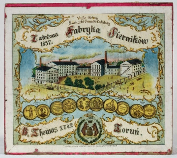 MT/P/110 Zewnętrzna strona wieka przedstawia w centralnej części wyobrażenie fabryki pierników, poniżej medale przyznane za produkty. Pod nimi napisy: „H. Thomas T.Z.O.P.” i „Toruń”, a także herb fabryki przedstawiający dwa niedźwiedzie w koronach stojące przy ulu. W górnej części wieka napis: „Założona 1857. Fabryka Pierników”.
