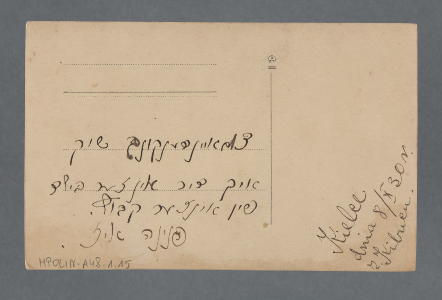 Fotografia - rozmazana, ale dość wyraźna - wywołana w sepii, kilkunastu osób, stojących lub siedzących, wśród których wiele jest ubranych w białe koszule, dwóch mężczyzn w tylnym rzędzie - w koszule ludowe (pasek ciągnący się z lewego ramienia pionowo). Najbliżej obiektywu grupka czterech osób, na przedzie grupki półleżąca kobieta ubrana na jasno. Po prawej stojący osobno mężczyzna w garniturze, roześmiany. Za zgromadzonymi budynek ceglany. Być może ten sam co na zdjęciu z nrem 1.11 w zespole.Krawędzie proste; przebarwienie w części dolnej krawędzi. Obraz kończy się przed górną krawędzią wskutek złego wywołania - stworzyło to nieco ukośny margines.