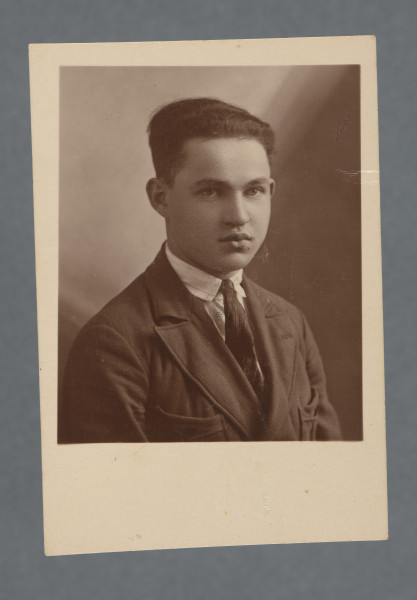 Fotograficzne popiersie młodego mężczyzny o zaczesanych do tyłu włosach, Mordki (Józefa) Englendera; twarz ujęta w trzech czwartych, koszula w paski z czarnym krawatem, nieco jaśniejsza od krawata marynarka. Fotografia monochromatyczna, w sepii, z szerokim marginesem u dołu, odbitka podłużnie prostokątna, samo zdjęcie - zbliżone do kwadratu (krawędzie boczne nieco dłuższe od dolnej i górnej). Krawędzie proste. Przy krawędzi dłuższej rewersu nr piórem - zakładu fot.? - 11189