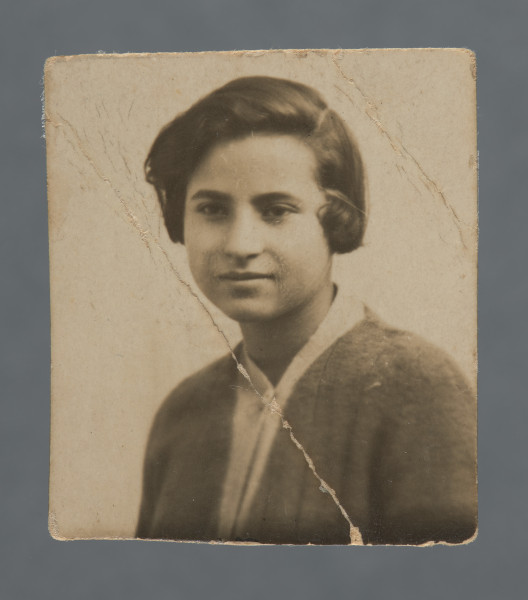 Fotografia młodej kobiety z ciemnymi włosami, zaczesanymi na bok (na prawo), popiersie, twarz ujęta w trzech czwartych; delikatny uśmiech. Ubrana w jasną bluzkę pod ciemnym rozpiętym sweterkiem (?). Zdjęcie z dwoma skośnymi przełamaniami.Krawędzie proste, nieznacznie nierówno przycięte. Niewykluczone, że jest to fragment większej fotografii grupowej.Na papierze Leonar. Oznaczenie firmowe bez pierwszej litery loga; pod nim widoczny fragment (?) nadrukowanego numeru: 8623.