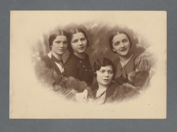 MPOLIN-A48.1.30 Monochromatyczna fotografia studyjna czterech młodych kobiet, popiersie, ubranych w wyjściowe suknie lub kostiumy. Włosy z trzech górnych, w tym Mani Żelaznej - najbardziej po lewej - z przedziałkiem, kobieta u dołu ma włosy zaczesane na bok, z falą. Zdjęcie wywołane w owalu z rozmytą krawędzią, nieznacznie bardziej w lewej części karty. Krawędzie proste.