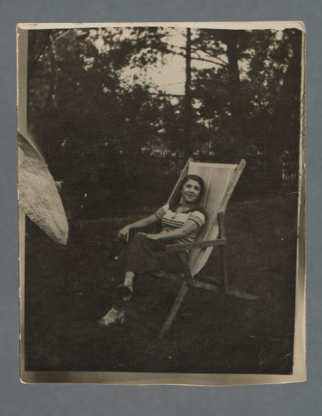 Monochromatyczna fotografia młodej kobiety - o imieniu Małgorzata, jak wynika z dedykacji - na leżaku w plenerze, za nią widoczne zarysy drzew. Siedzi z nogą założoną na nogę, patrzy w obiektyw.Zdjęcie wywołane z marginesem, nie jest on zupełnie równy, nie jest też zupełnie równo przycięte. Po lewej stronie podobizna liścia, jednak wychodzącego przed margines przy krawędzi - element fotomontażu, którego reszta nie zachowała się, ponieważ zdjęcie po lewej zostało przycięte? Krawędzie nieząbkowane.