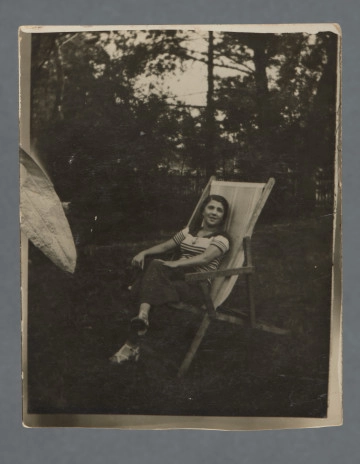 Monochromatyczna fotografia młodej kobiety - o imieniu Małgorzata, jak wynika z dedykacji - na leżaku w plenerze, za nią widoczne zarysy drzew. Siedzi z nogą założoną na nogę, patrzy w obiektyw.Zdjęcie wywołane z marginesem, nie jest on zupełnie równy, nie jest też zupełnie równo przycięte. Po lewej stronie podobizna liścia, jednak wychodzącego przed margines przy krawędzi - element fotomontażu, którego reszta nie zachowała się, ponieważ zdjęcie po lewej zostało przycięte? Krawędzie nieząbkowane.